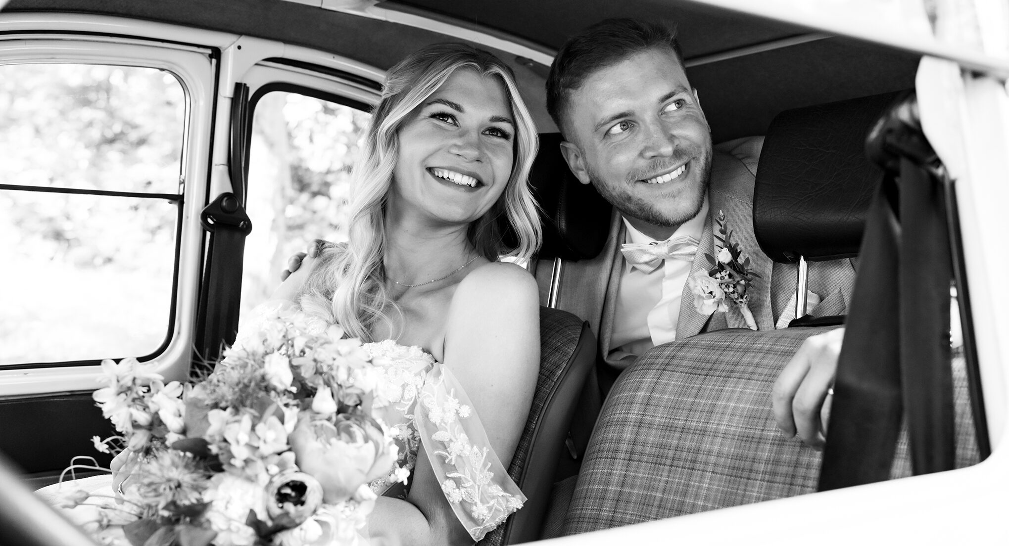 Glückliches Hochzeitspaar strahlt im Oldtimer nach der Trauung in Dortmund